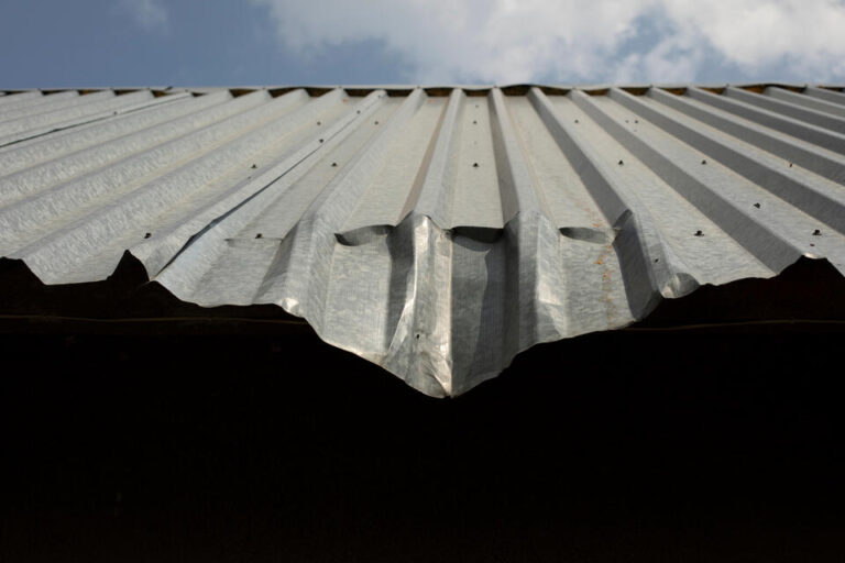 metal roof repair-close up of damaged corrugated metal roof on a house