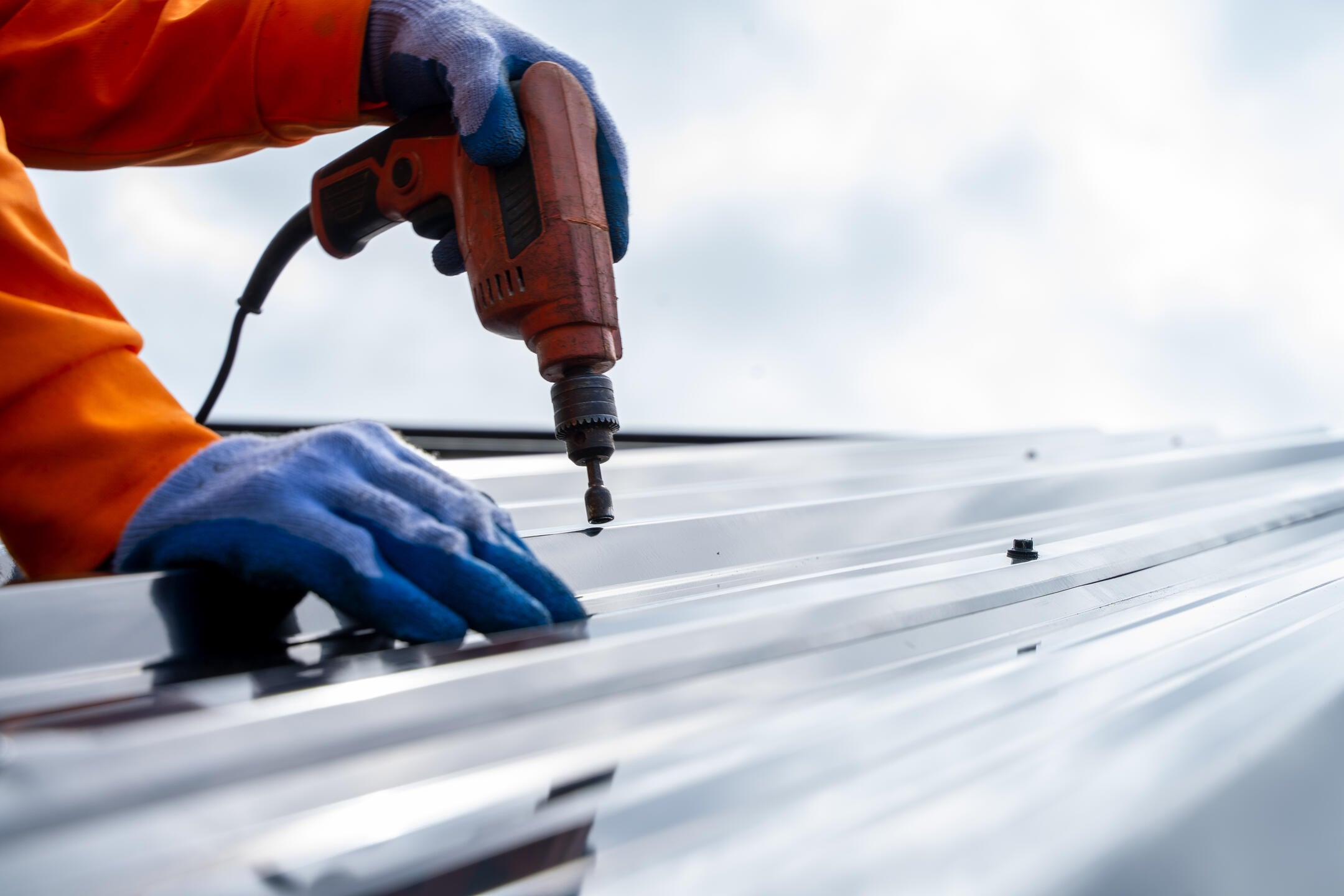 metal roof repair-close up of roofer repairing a section of corrugated metal roofing