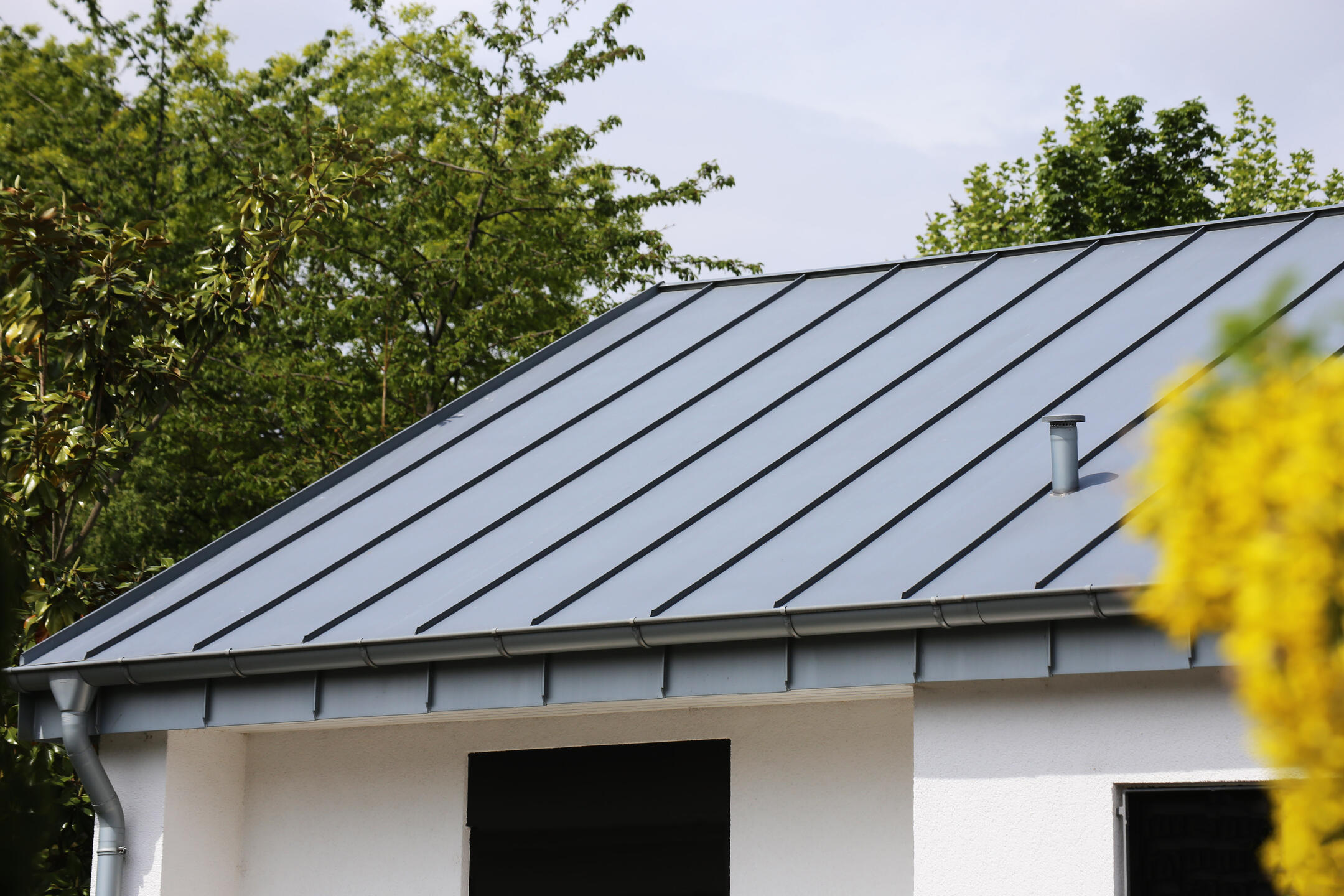 metal roof vs shingles-white house with gray standing seam metal roofing