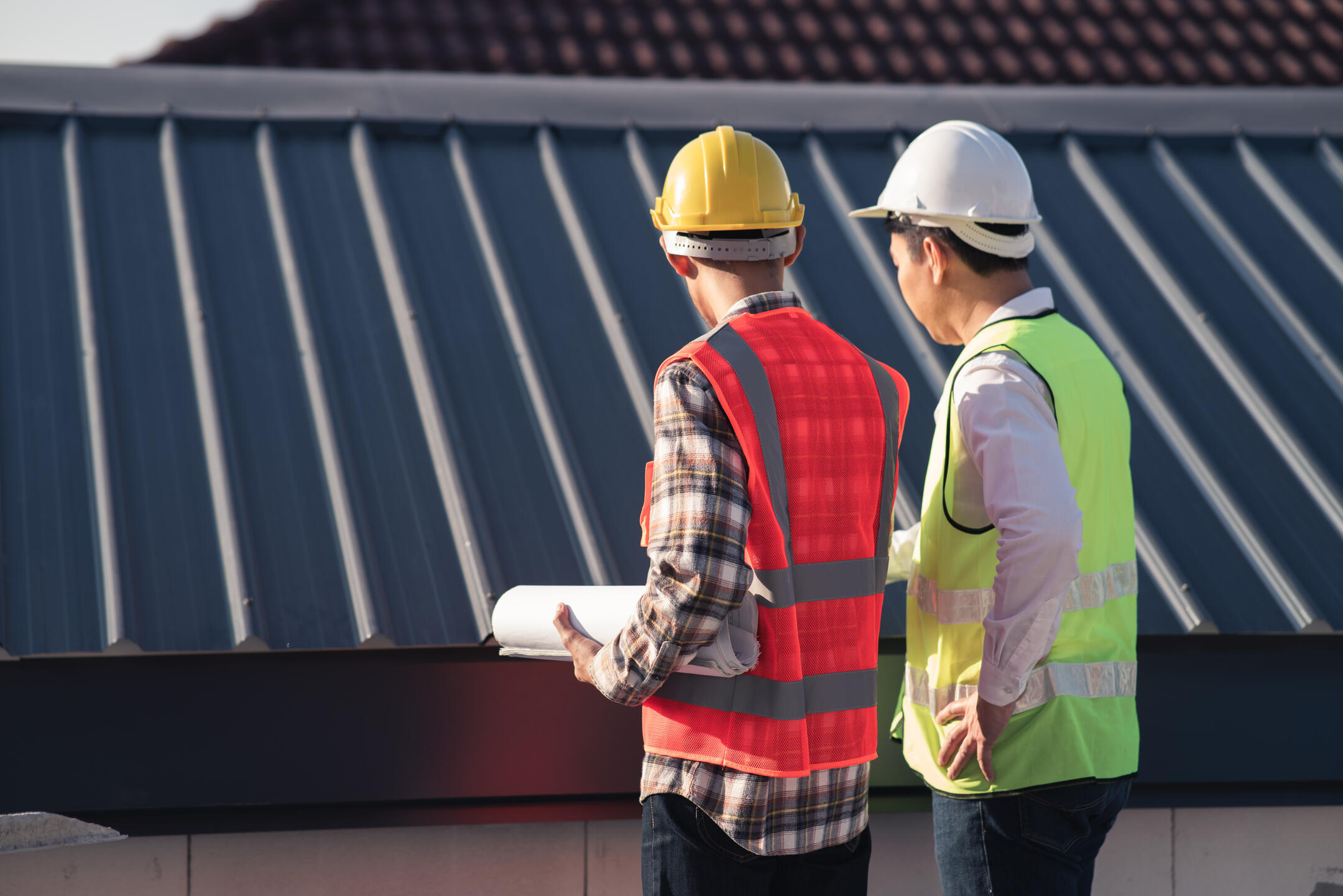 roof inspection cost-two inspectors reviewing a metal roof