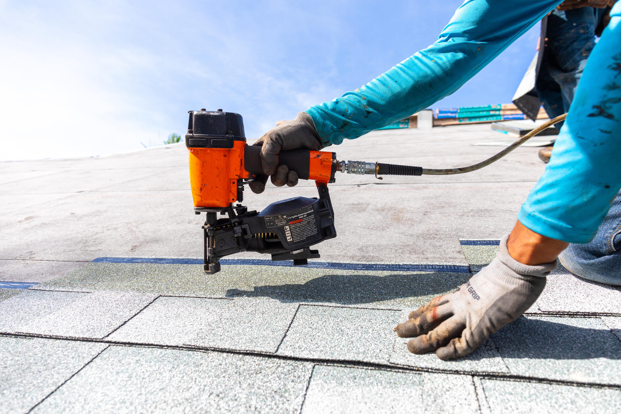 roof installation-close up of roofer installing shingles with power tools