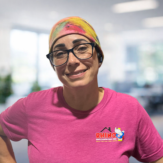 A person wearing glasses, a colorful headscarf, and a pink 
